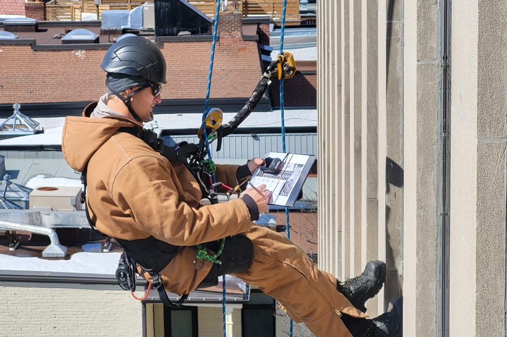 Image de cordiste descendant le long d'un mur extérieur en rappel.